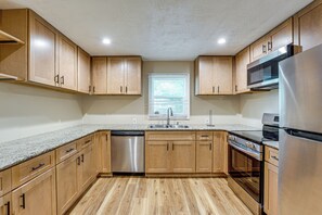 A modern kitchen with wooden cabinets, stainless steel appliances, and a granite countertop. - Kennesaw Home Near KSU & Lake Acworth (Kennesaw)