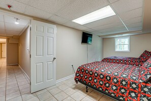 A bedroom with a bed, a door, a television on the wall, and a window. - Kennesaw Home Near KSU & Lake Acworth (Kennesaw)