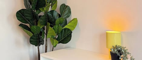 A white desk with a mirror above it, a yellow lamp, and a potted plant.