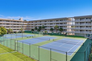 Un hotel de varios pisos con instalaciones de tenis.