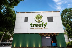 Un edificio con fachada verde y blanca, un logo con un árbol y el texto 'treefy by United'.