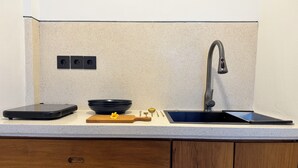 A kitchen with a modern faucet, a black bowl, a digital scale, and a wooden cutting board.
