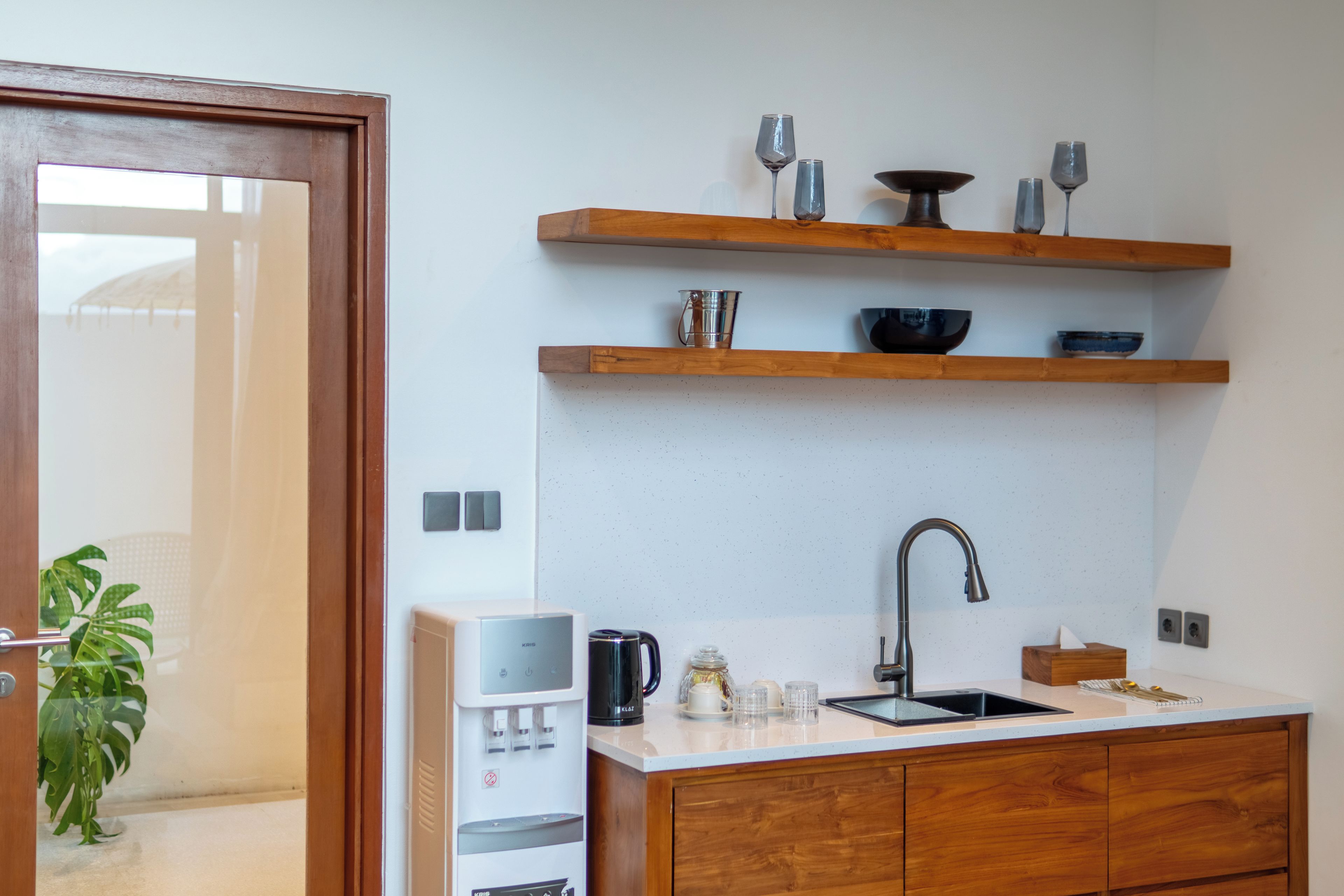 A modern kitchen with wooden cabinets, a stainless steel sink, and a water dispenser.