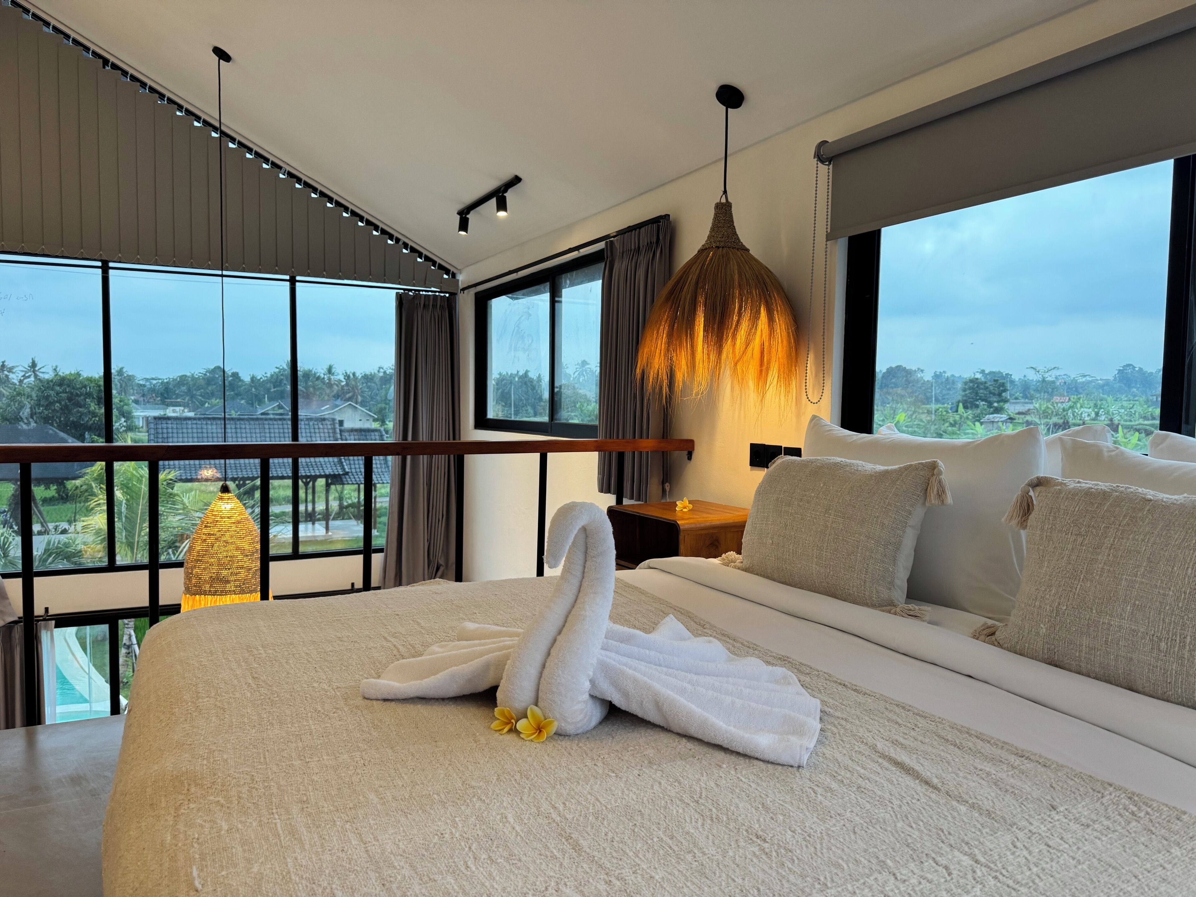 Ein modernes Hotelzimmer mit einem großen Bett, Blick auf die Landschaft und einer außergewöhnlichen Pendelleuchte.