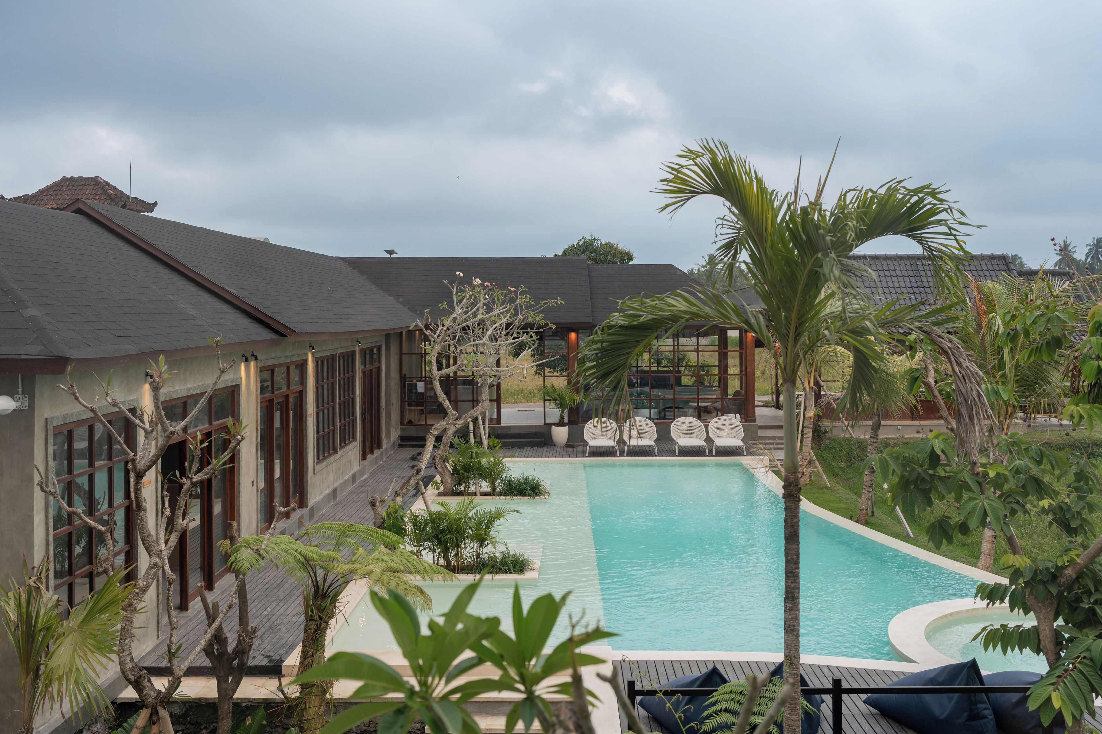 A pool area with a clear view of the pool, lounge chairs, and surrounding vegetation.