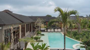 A pool area with a clear view of the pool, lounge chairs, and surrounding vegetation.