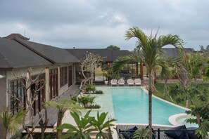 A pool area with a clear view of the pool, lounge chairs, and surrounding vegetation. - The Santa Ubud (Ubud)