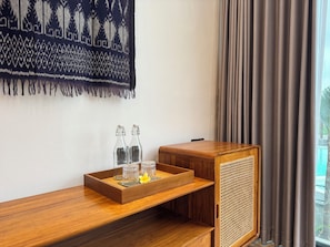 A wooden console table with a tray, two glass bottles, and a small yellow flower.