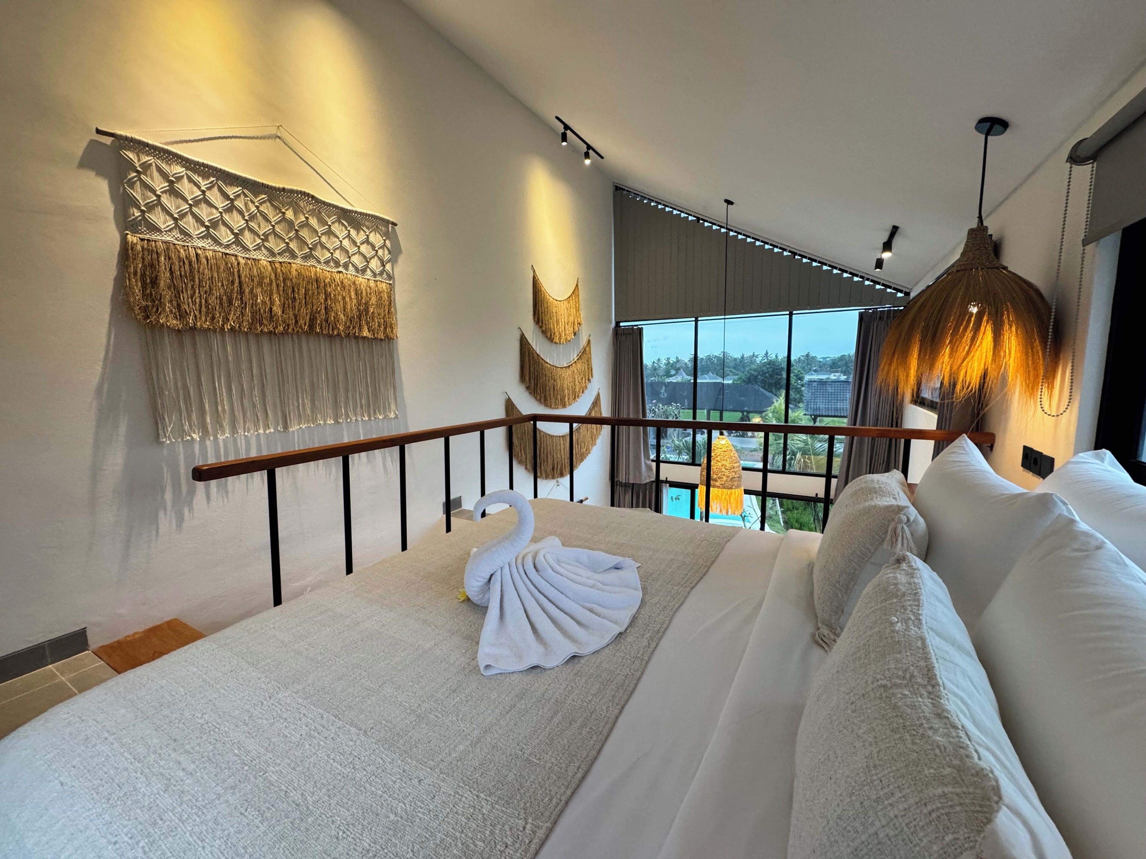 A bedroom with a bed, a balcony, and a view of the outdoors.