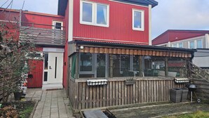 A red two-story house with a covered porch and a small garden area. - Malmoxie Unic garden House (Malmö)