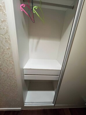 Ein weißer Kleiderschrank mit Kleiderstange und Ablagefläche.