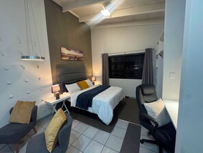 Une chambre d’hôtel moderne, équipée d’un lit, de tables de chevet, d’un bureau, d’une chaise et d’une fenêtre avec des rideaux.