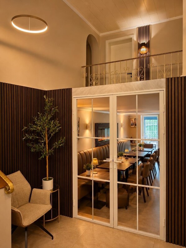 Un interior moderno con una zona de estar, una mesa de comedor y una escalera que sube a un nivel superior.