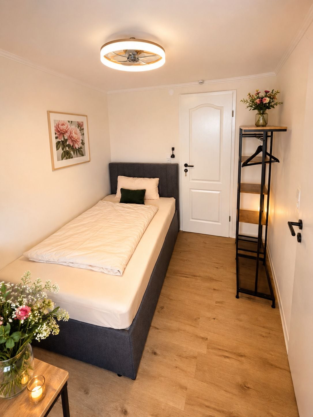 Ein Schlafzimmer mit Bett, Nachttisch und einer Wandregal mit Kleiderhaken.