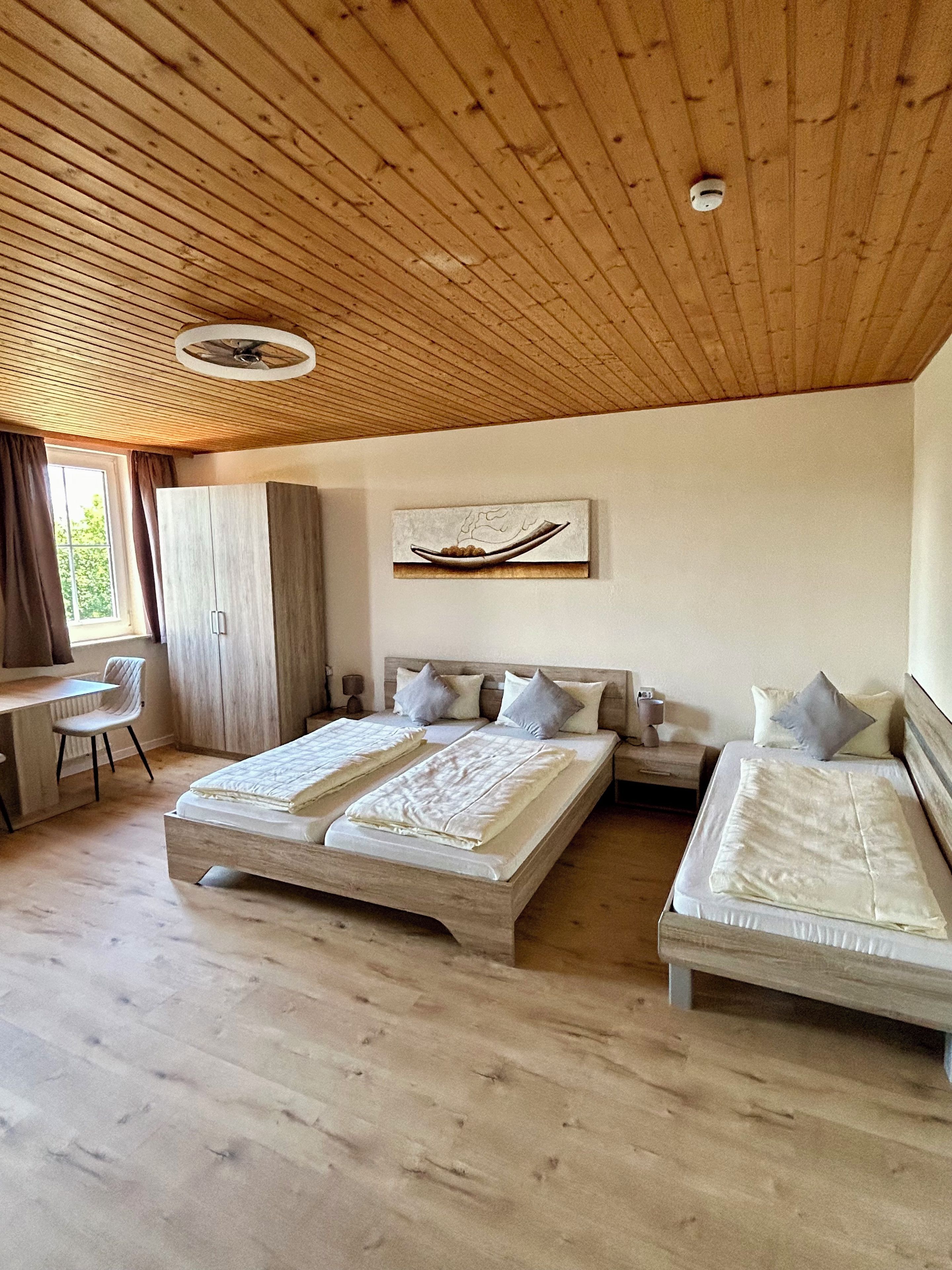 A bedroom with two beds, a desk, and a chair.