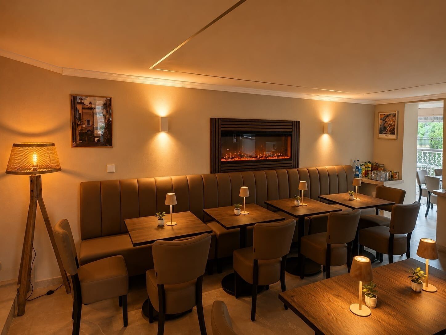 En restaurang med en lång bänkrad för sittplatser, flera bord och en öppen spis.