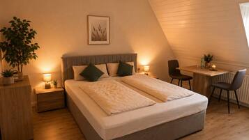 A bedroom with a bed, bedside tables, a desk, and a chair.