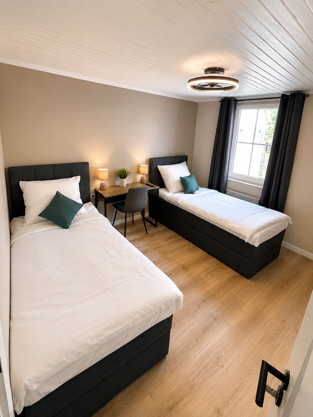 Habitación de hotel con dos camas, un escritorio y una silla.