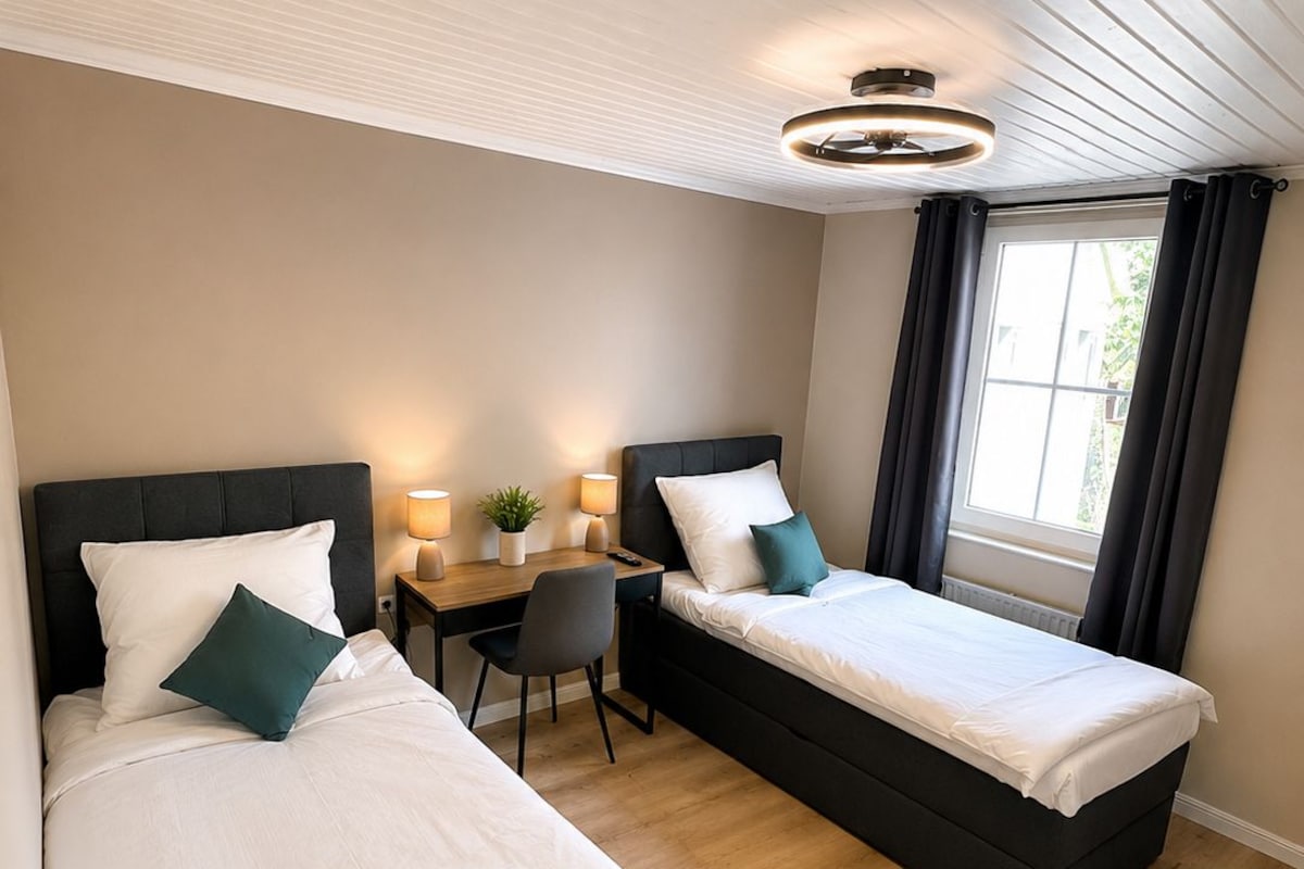 A hotel room with two beds, a desk, and a chair.