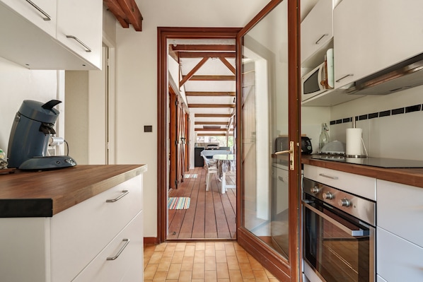 Una cocina estrecha con vigas de madera, una cafetera y un microondas.