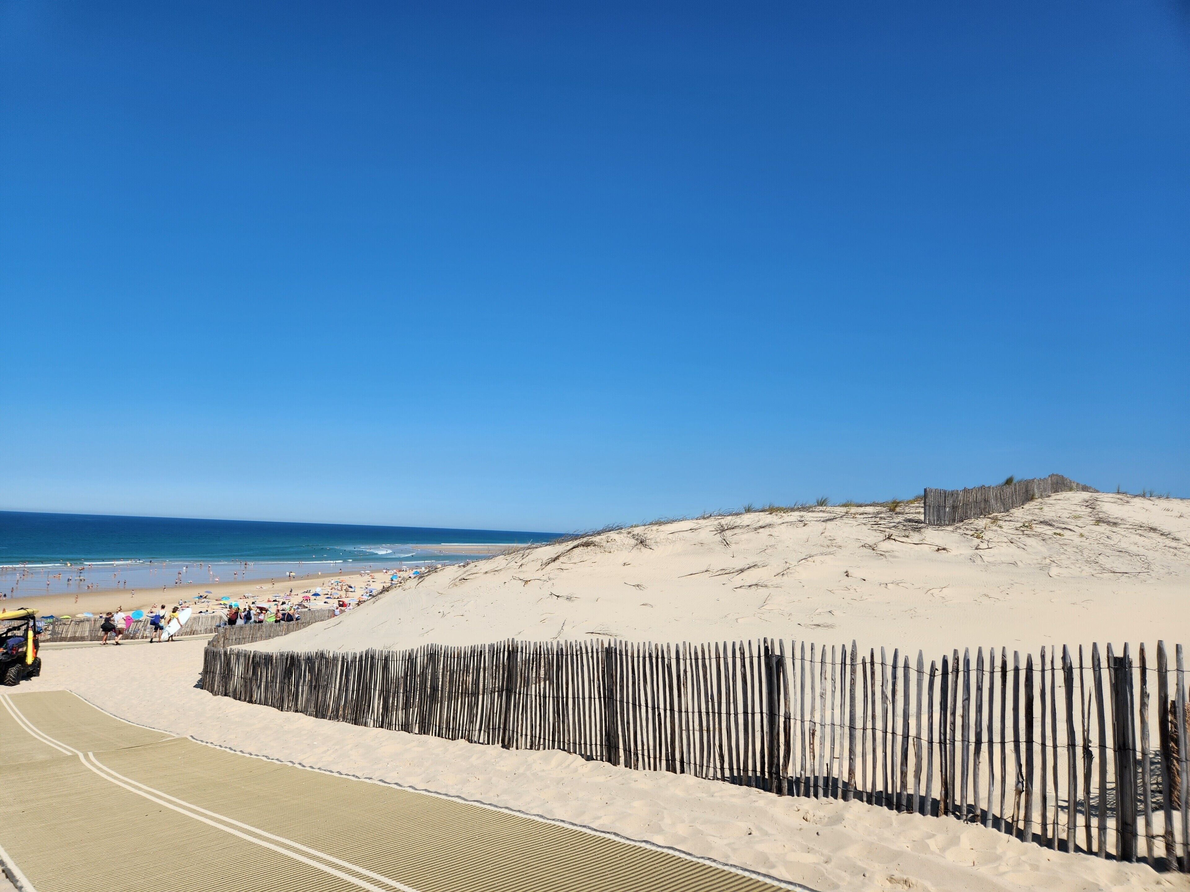 A sandy beach with a wooden fence and a clear blue sky.