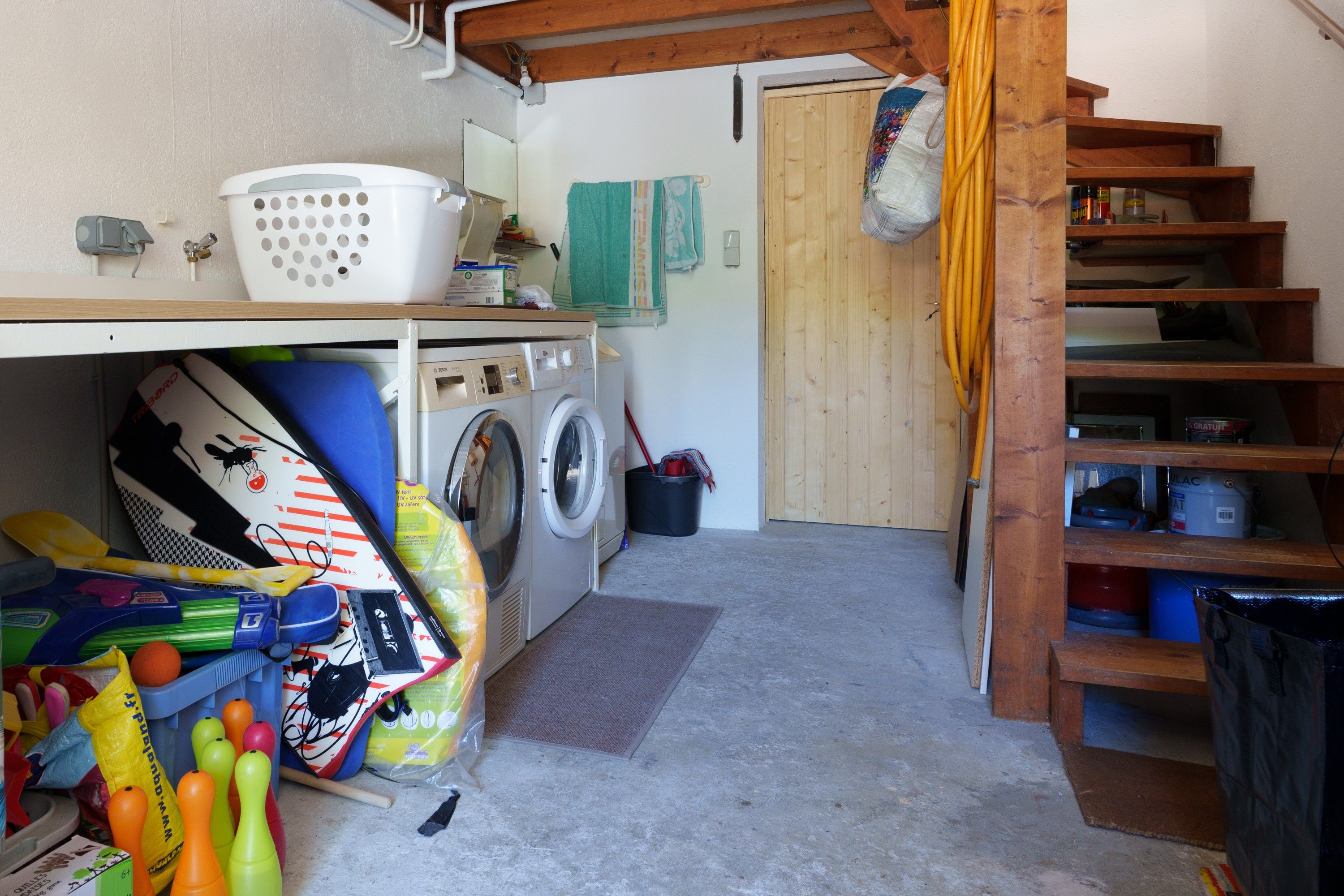 Een wasserette met een wasmachine, droger en een houten plank met diverse spullen.