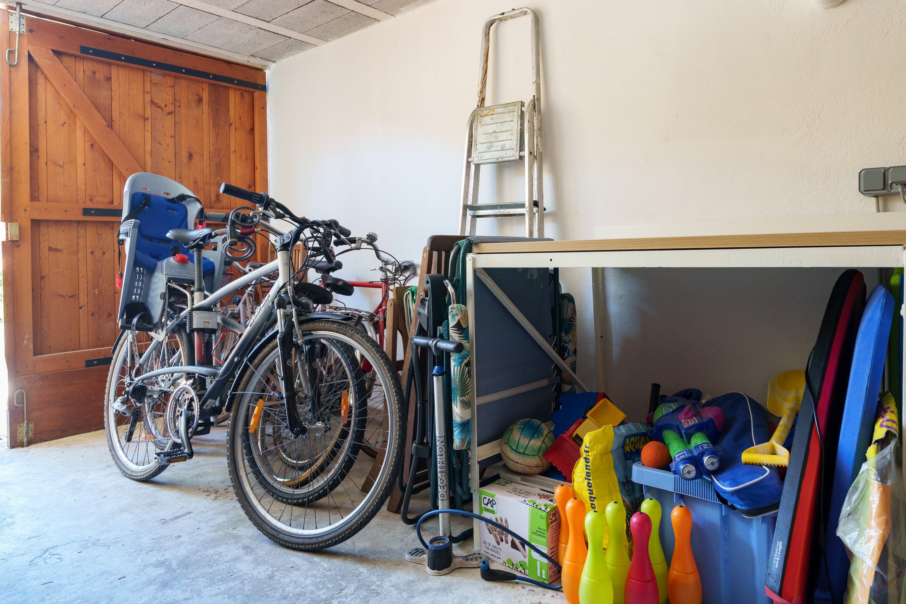 A garage with bicycles, a ladder, and various sports equipment.