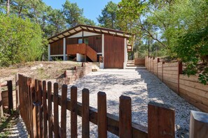 Una cabaña de madera con un camino de grava que conduce a ella, rodeada de árboles.
