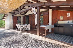 Un patio exterior con mesa y sillas, una pérgola de madera y una cocina con pileta y armarios.