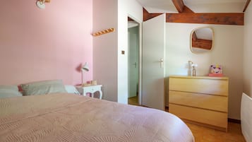 A bedroom with a bed, bedside table, dresser, and a mirror on the wall.