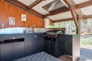 A modern kitchen with a built-in stove, a sink, and wooden paneling on the walls.