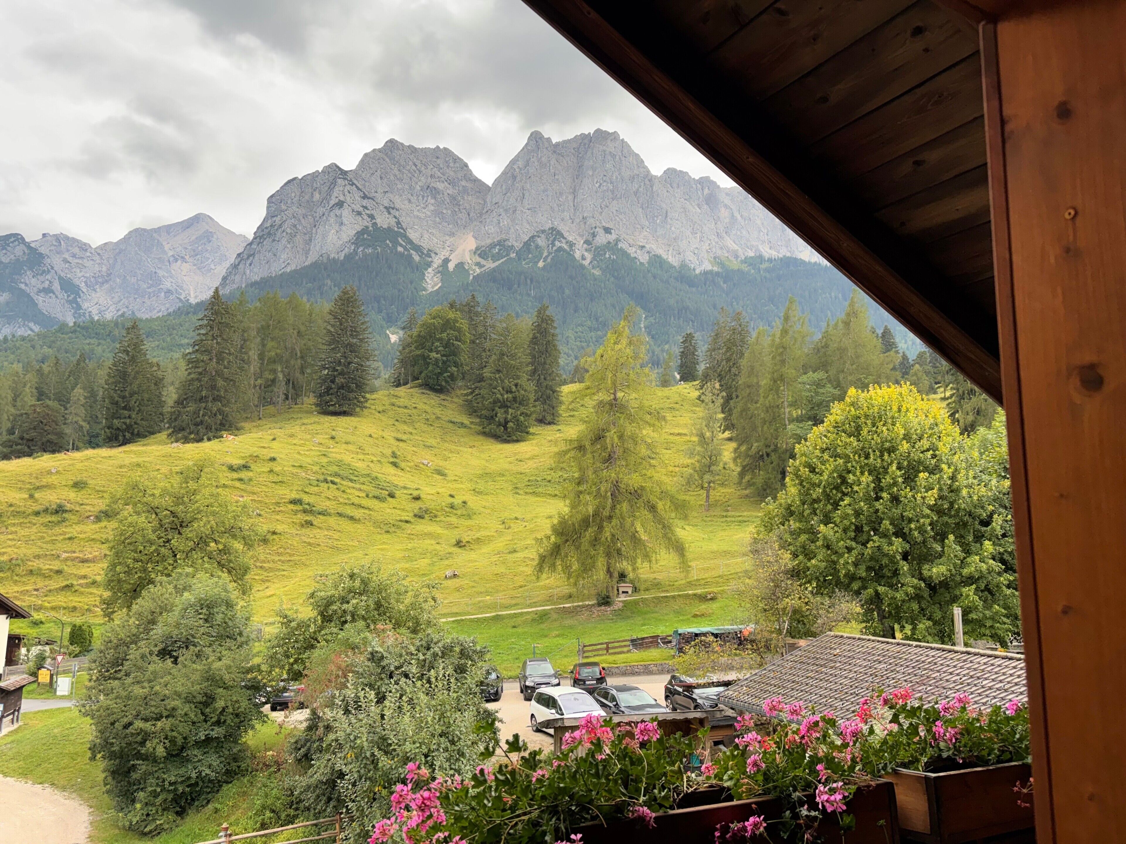 Une vue depuis un balcon en bois donnant sur une vallée verdoyante, avec des montagnes en arrière-plan.