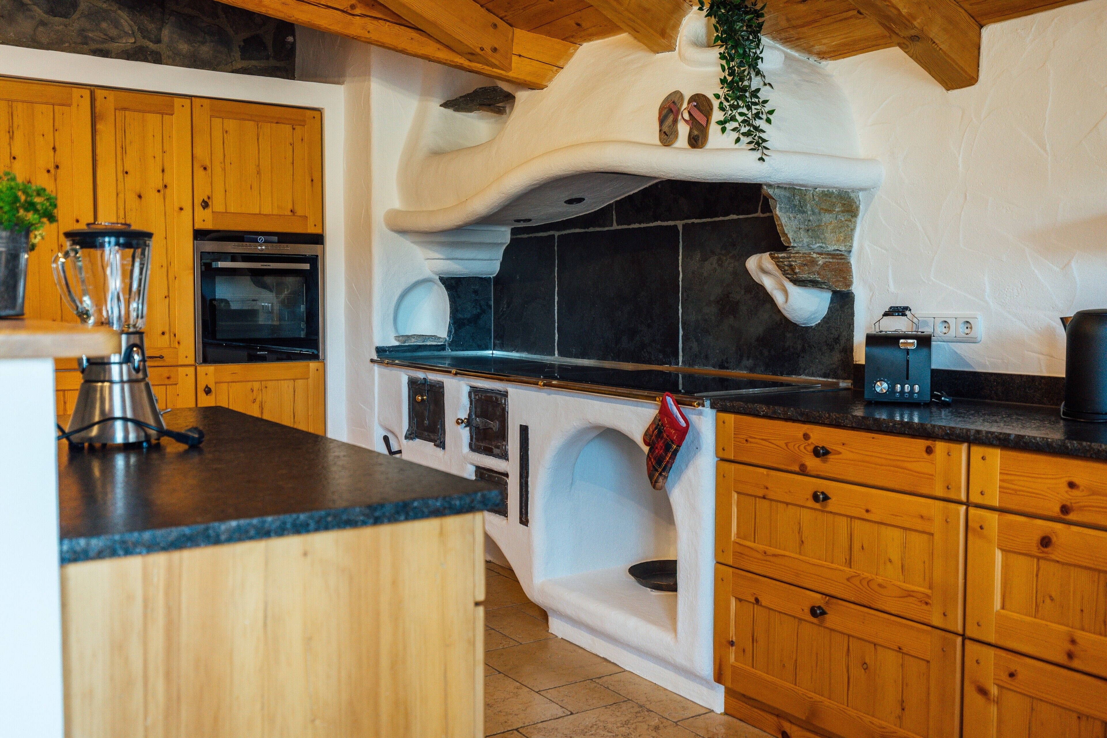 Una cocina con armarios de madera, horno empotrado, cafetera y licuadora sobre la encimera.
