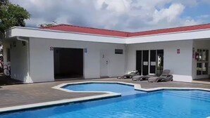 Piscina com espreguiçadeiras e área coberta com telhado vermelho.