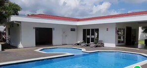 Ein Schwimmbad mit Liegestühlen und einem überdachten Bereich mit rotem Dach.