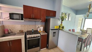 Cozinha compacta com micro-ondas, fogão, forno e geladeira.