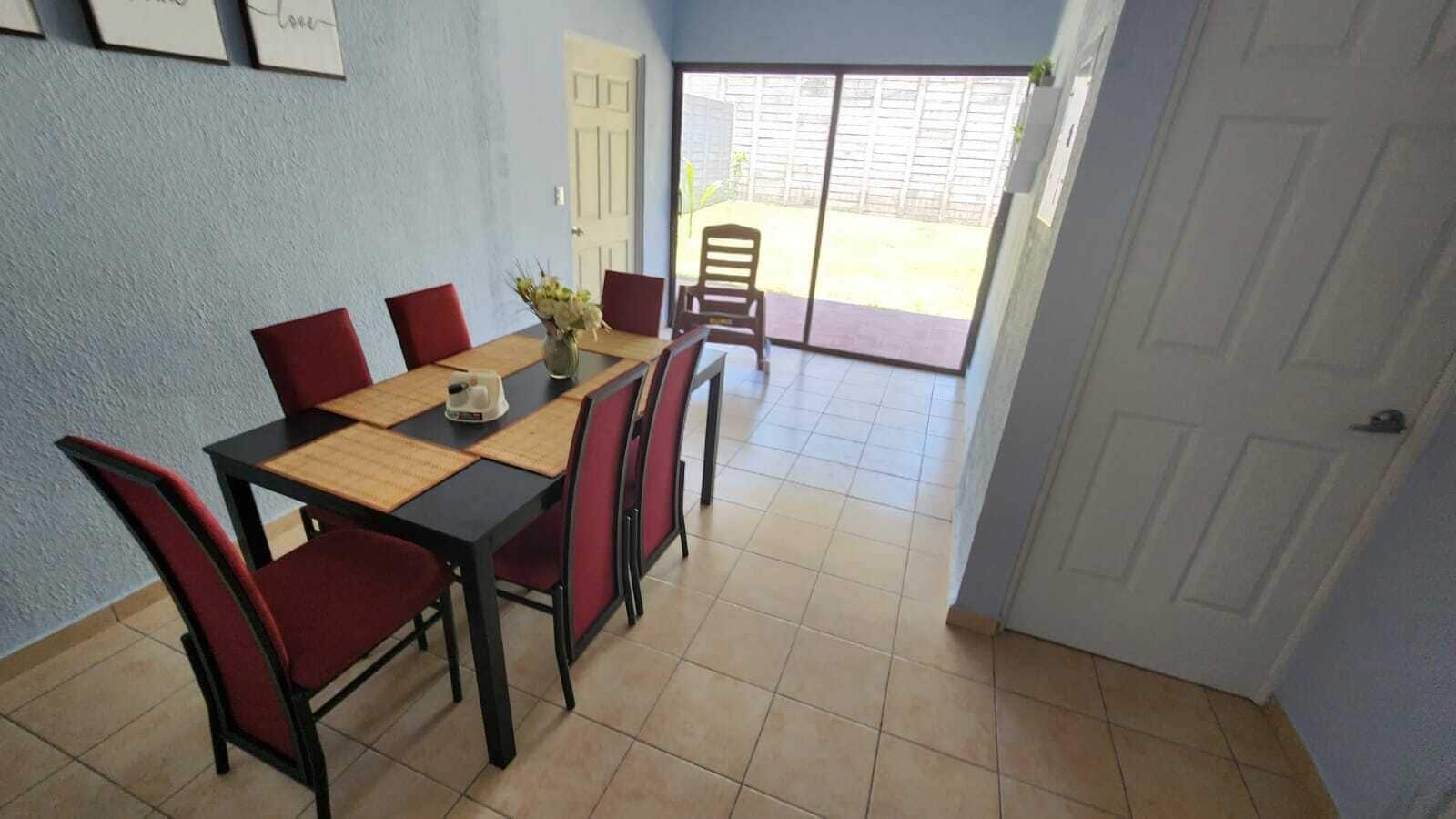 A dining area with a table and chairs, a door leading to a patio, and a tiled floor.