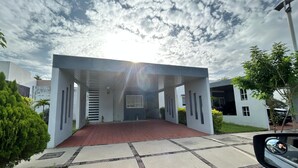 Um edifício moderno com entrada coberta, um caminho de acesso pavimentado e céu claro.