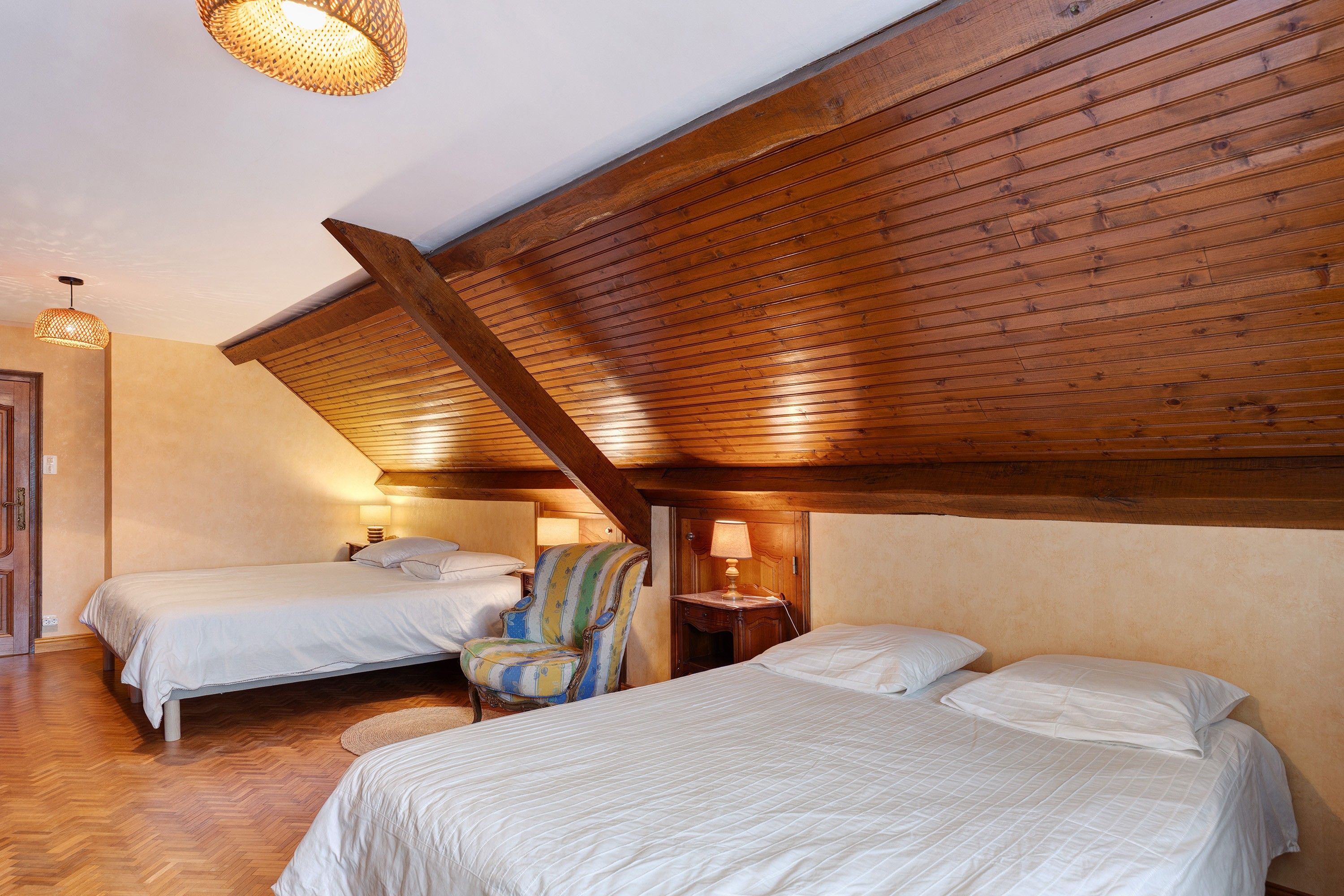 Une chambre d’hôtel avec deux lits, une chaise et une lampe.