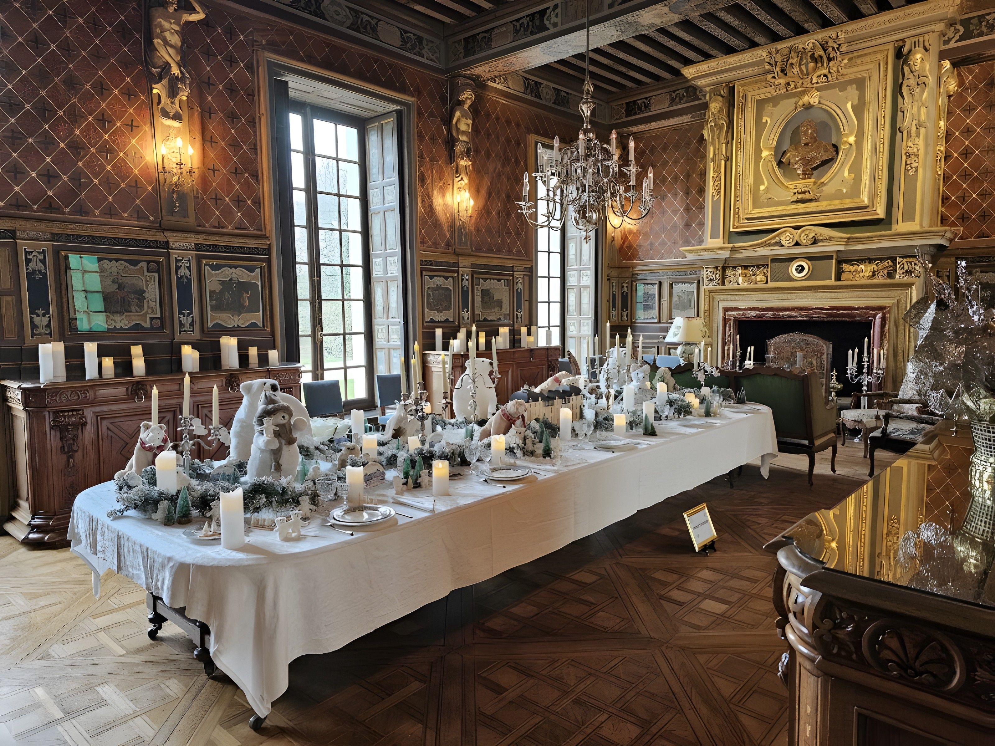 Een lange eettafel gedekt met kaarsen en wit servies, omringd door sierlijk meubilair en een open haard.
