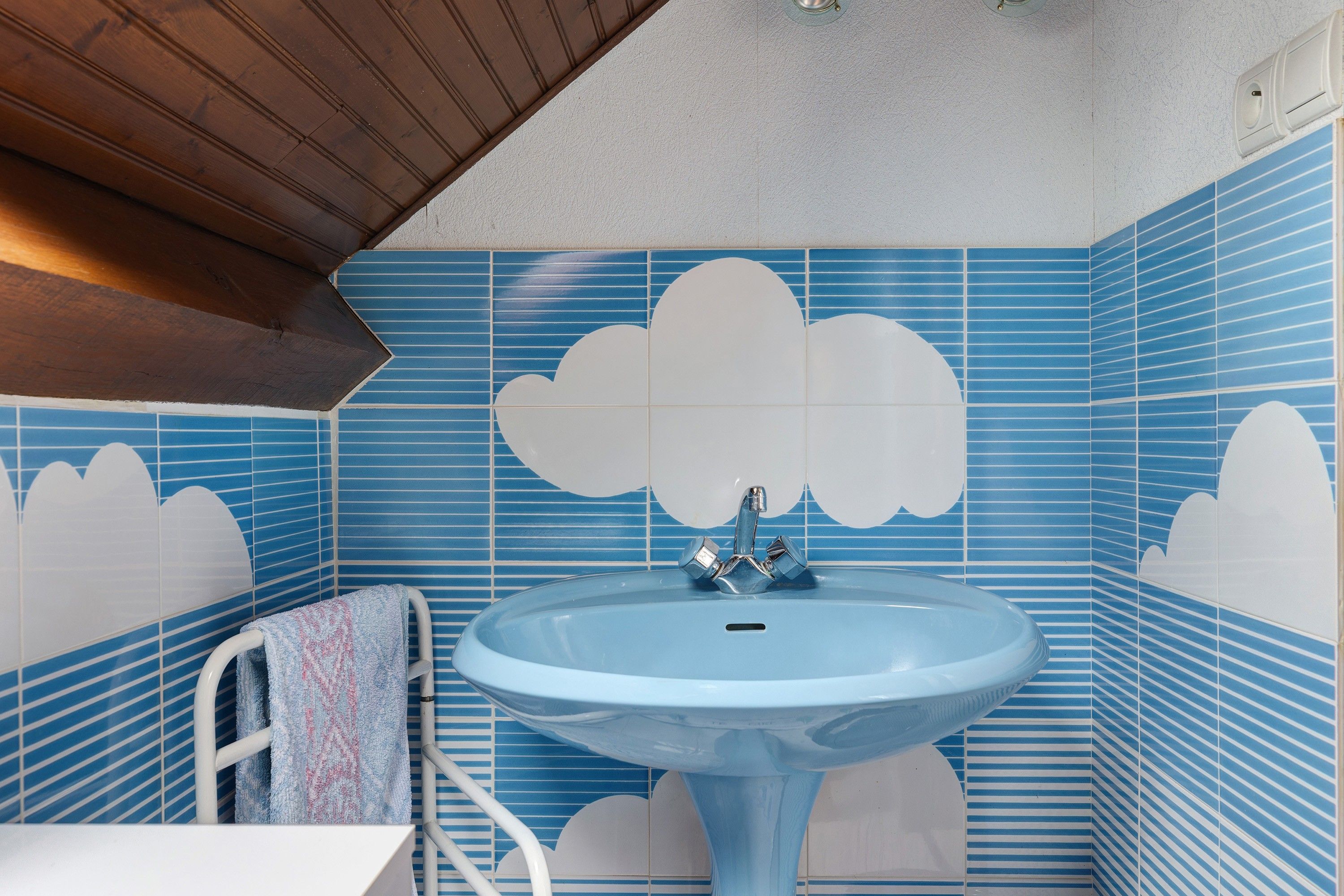 Een badkamer met een blauwe wastafel, een witte handdoek en blauw gestreepte tegels.