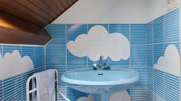 Een badkamer met een blauwe wastafel, een witte handdoek en blauw gestreepte tegels.