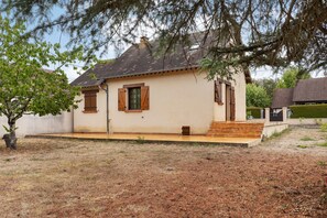 A single-story building with a tiled roof, a small porch, and a tree in the foreground.