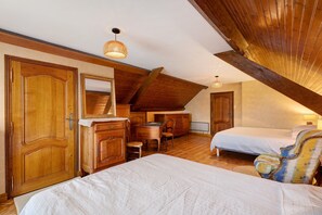 Ein Schlafzimmer mit schrägverdachter Decke, Holzmöbeln und einem Bett mit weißer Bettdecke.