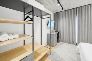 A modern hotel room with a bed, a desk, and a wardrobe with shelves. - Room-oceanfront Bliss With Breathtaking (Cape Town)