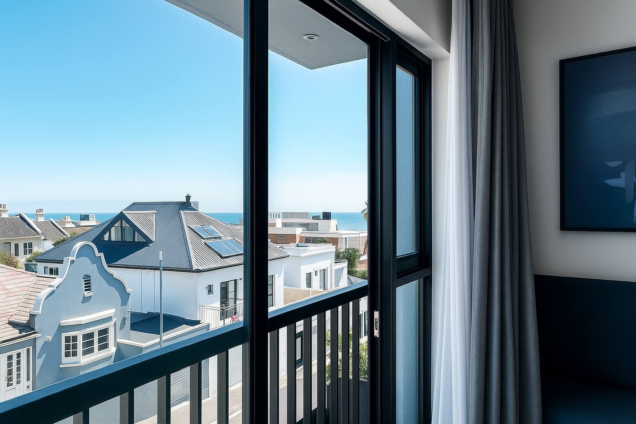 A balcony with a view of the sea and neighboring buildings.