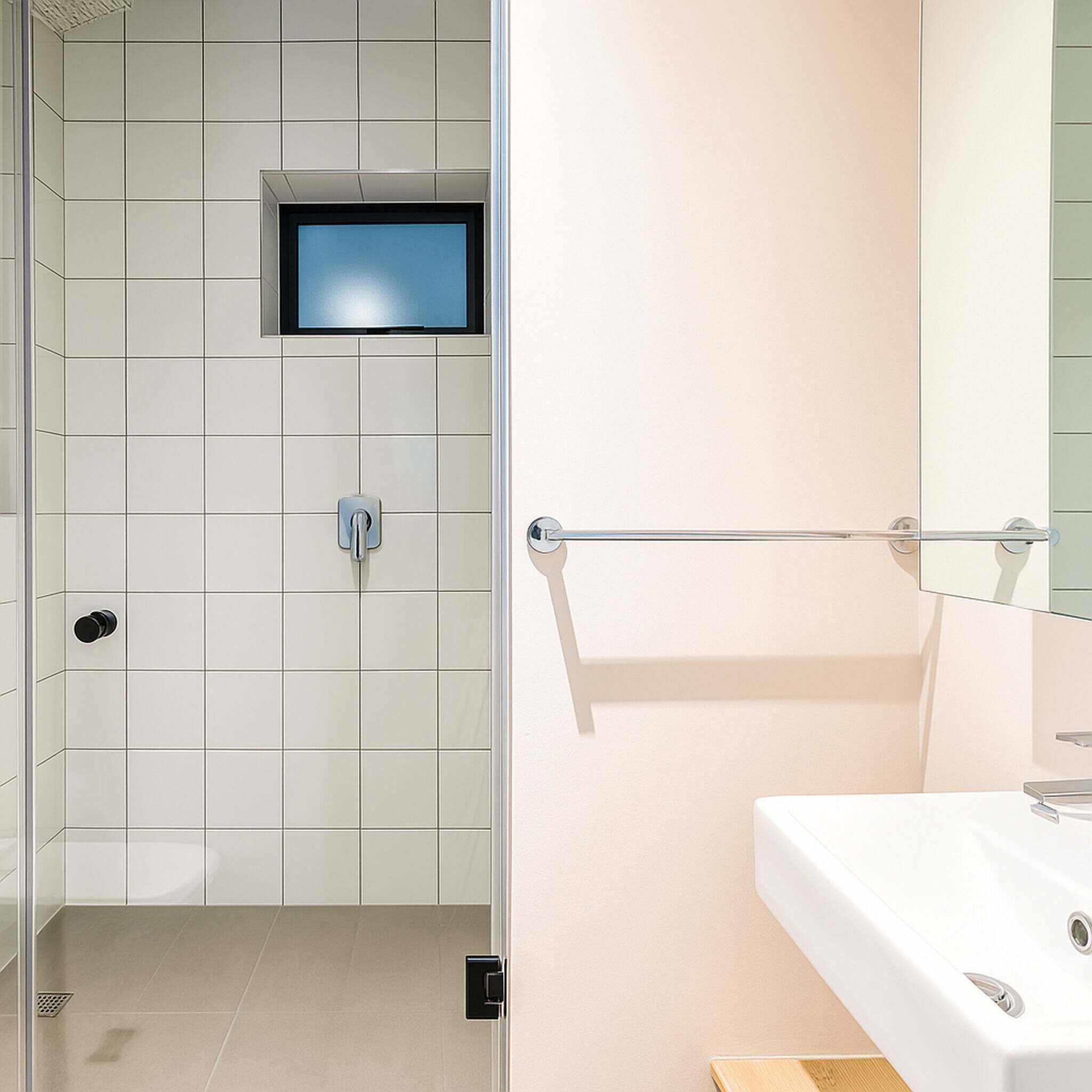 A modern bathroom with a shower, a sink, and a mirror.