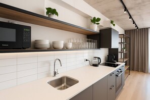 Eine moderne Küche mit Spüle aus Edelstahl, einem eingebauten Mikrowellenherd und einer Kaffeemaschine.