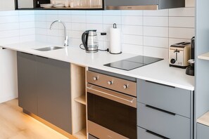 A modern kitchen with a built-in dishwasher, oven, and a coffee maker on the countertop. - Room-oceanfront Bliss With Breathtaking (Cape Town)