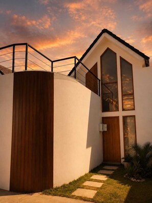 A modern house with a large wooden gate, a staircase leading to a deck, and a view of the sky. - Monstera A10 (Kerobokan , Seminyak)